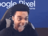a man is sticking his tongue out while sitting in a chair in front of a blue wall.gif