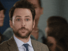 Movie gif. Wearing a brown suit jacket, Charlie Day gives us a blank look as several people walk by him in the background. After a second, he raises a hand to give us a thumbs up, then walks out of frame. Movie gif. Wearing a brown suit jacket, Charlie Day gives us a blank look as several people walk by him in the background. After a second, he raises a hand to give us a thumbs up, then walks out of frame.